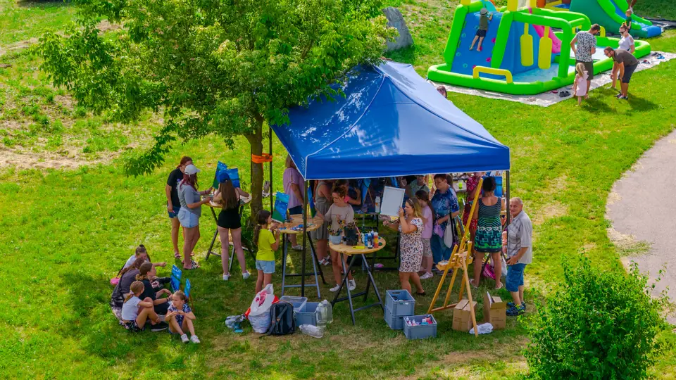 Letecký pohľad na park v Žiranoch s modrým stanom, v ktorom ľudia maľujú pri štafelajoch